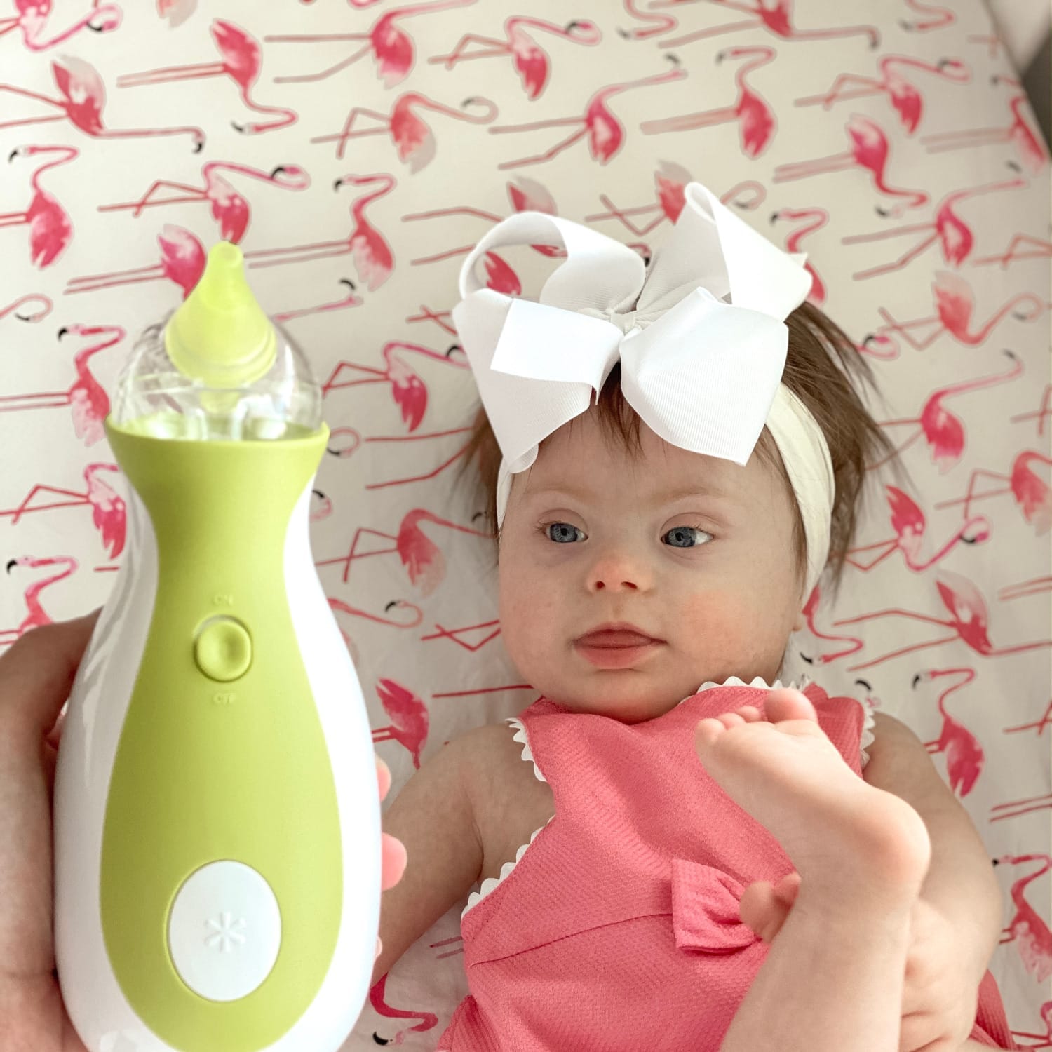 Bambina con sindrome di Down che guarda un aspiratore nasale elettrico portatile Nosiboo Go