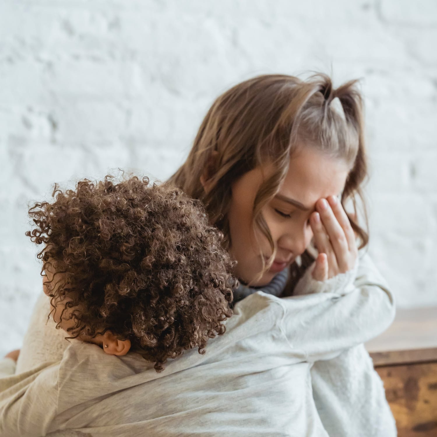 Una donna preoccupata si tocca la testa mentre abbraccia il suo bambino.